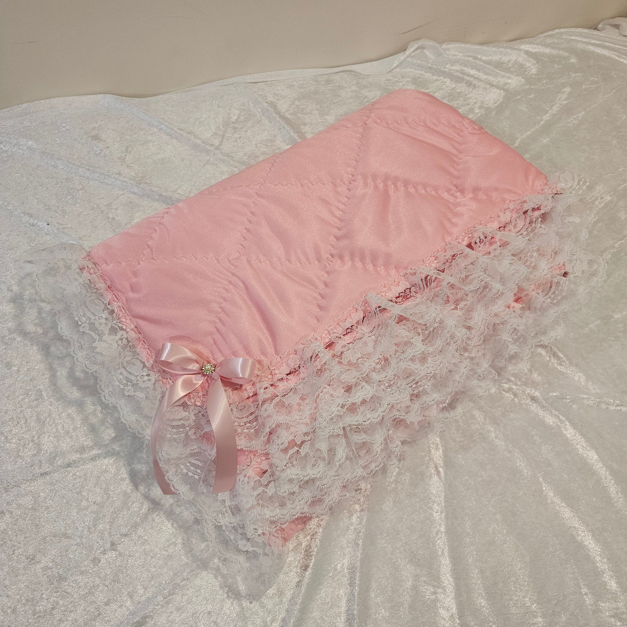 Pink minky snuggle blanket with lace trim on a textured white surface