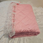 Pink minky  snuggle quilt with lace trim on a textured surface