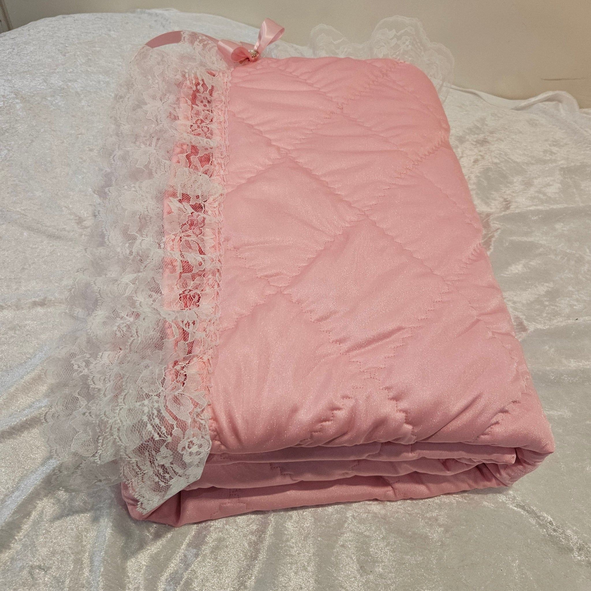 Pink minky  snuggle quilt with lace trim on a textured surface