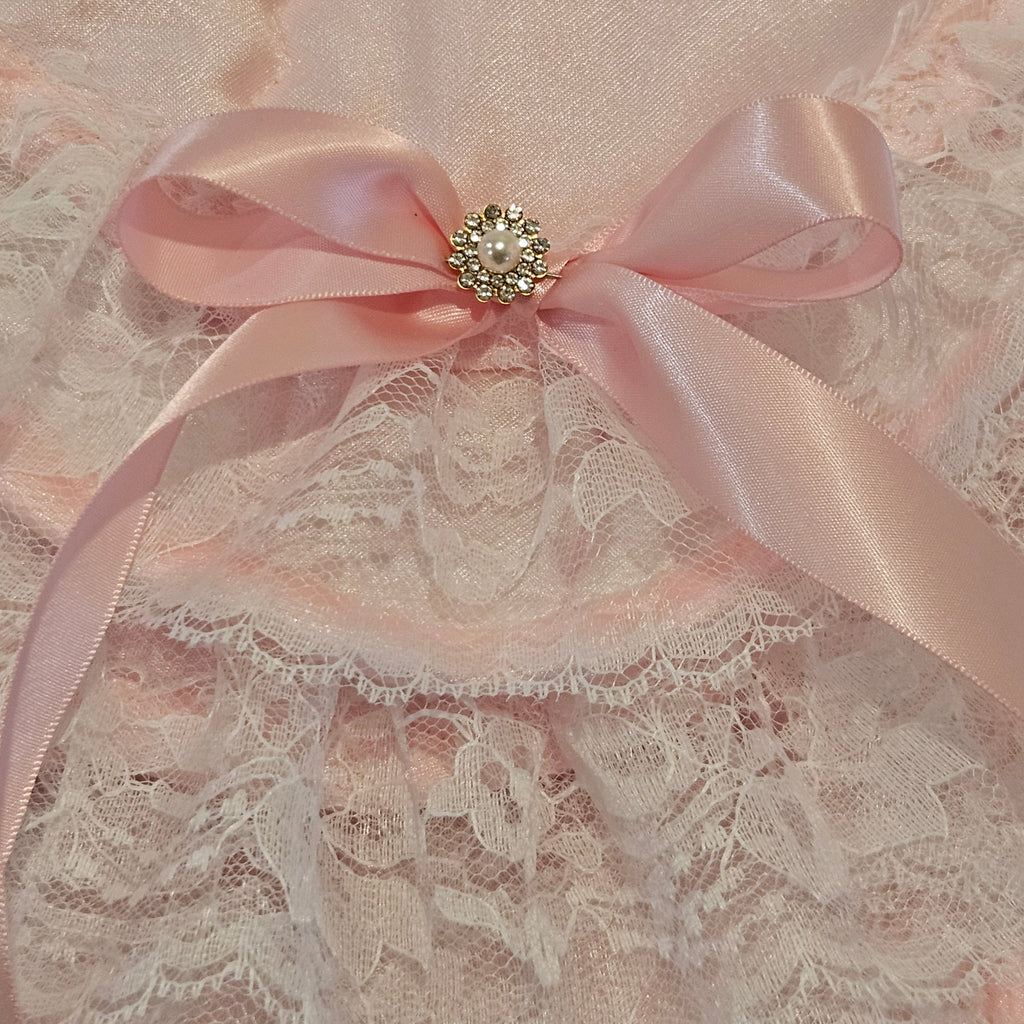 Pink satin ribbon with a decorative brooch on a lace fabric background