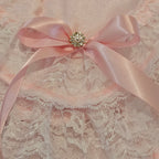 Pink satin ribbon with a decorative brooch on a lace fabric background