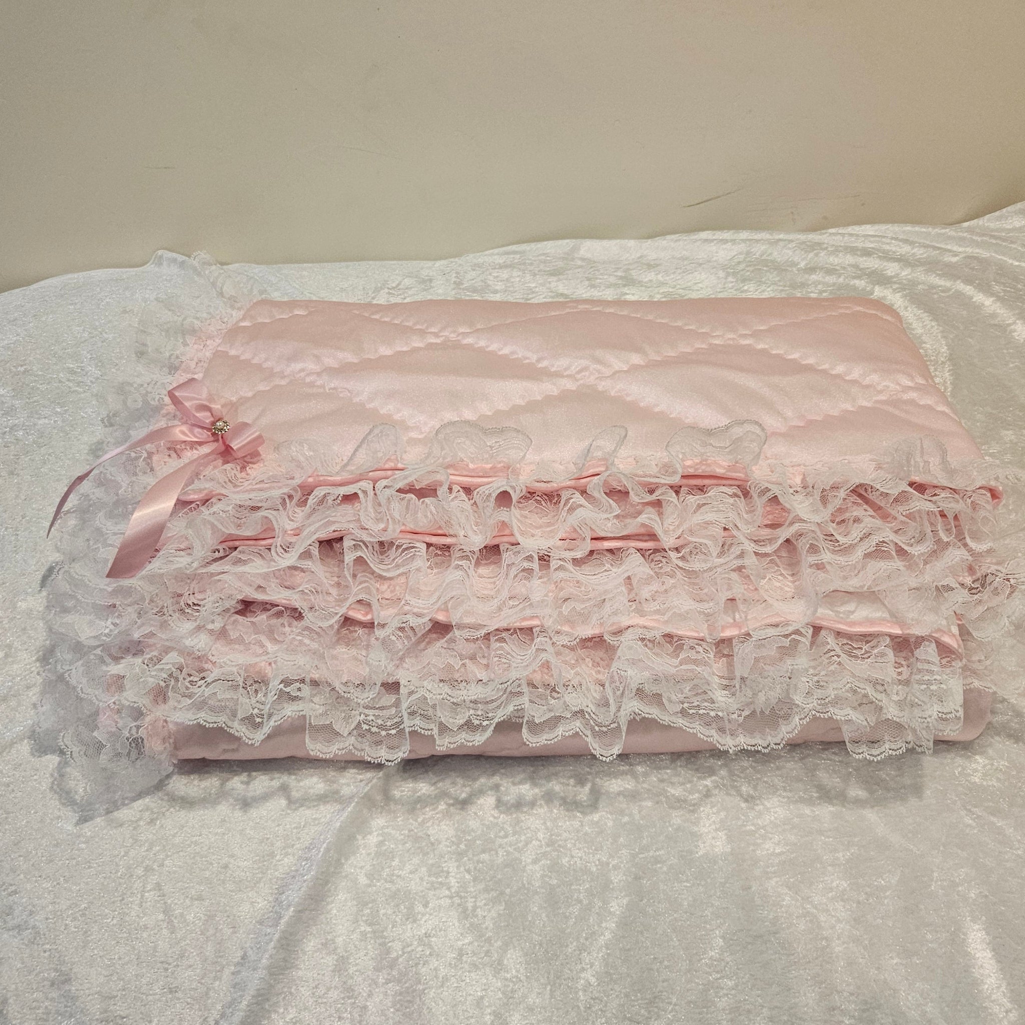 Pink lace snuggle blanket on a textured white surface