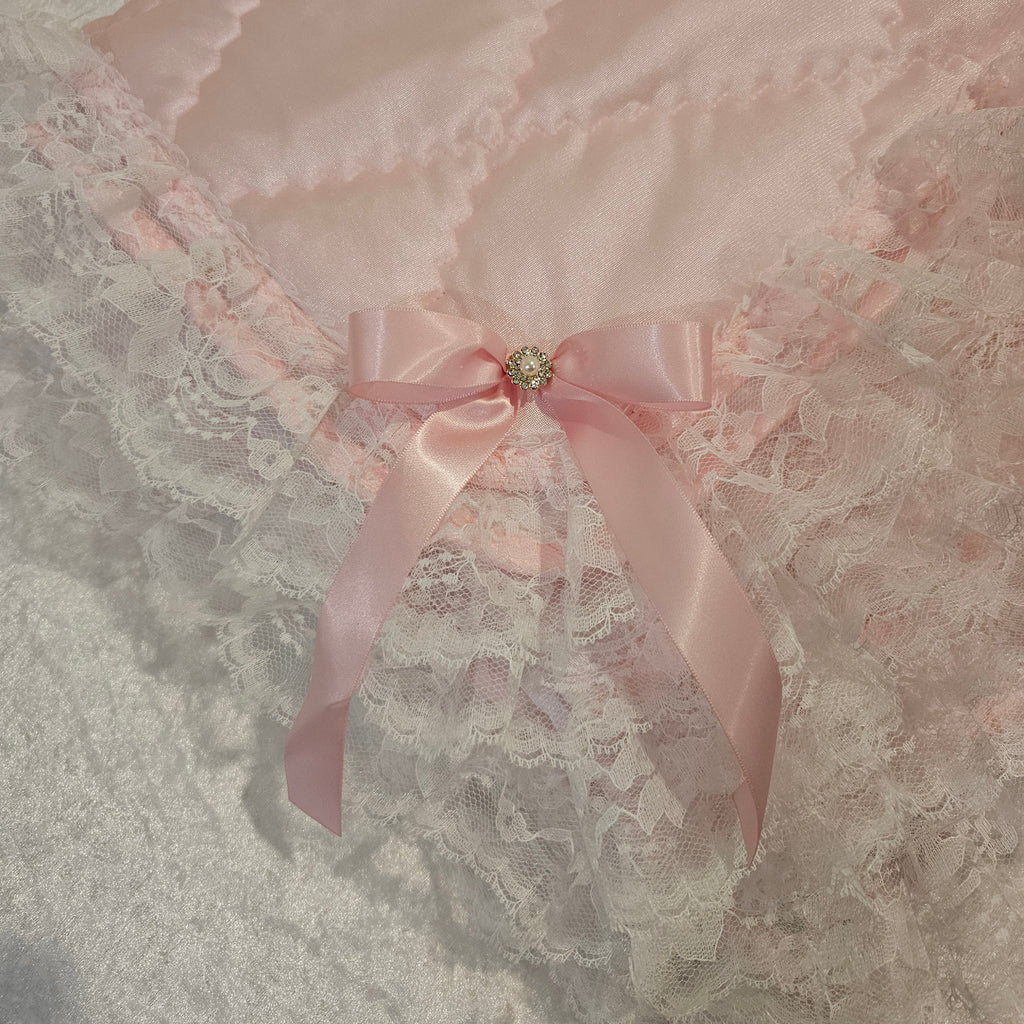 Close-up of a pink bow and lace with a decorative blanket on a textured fabric background