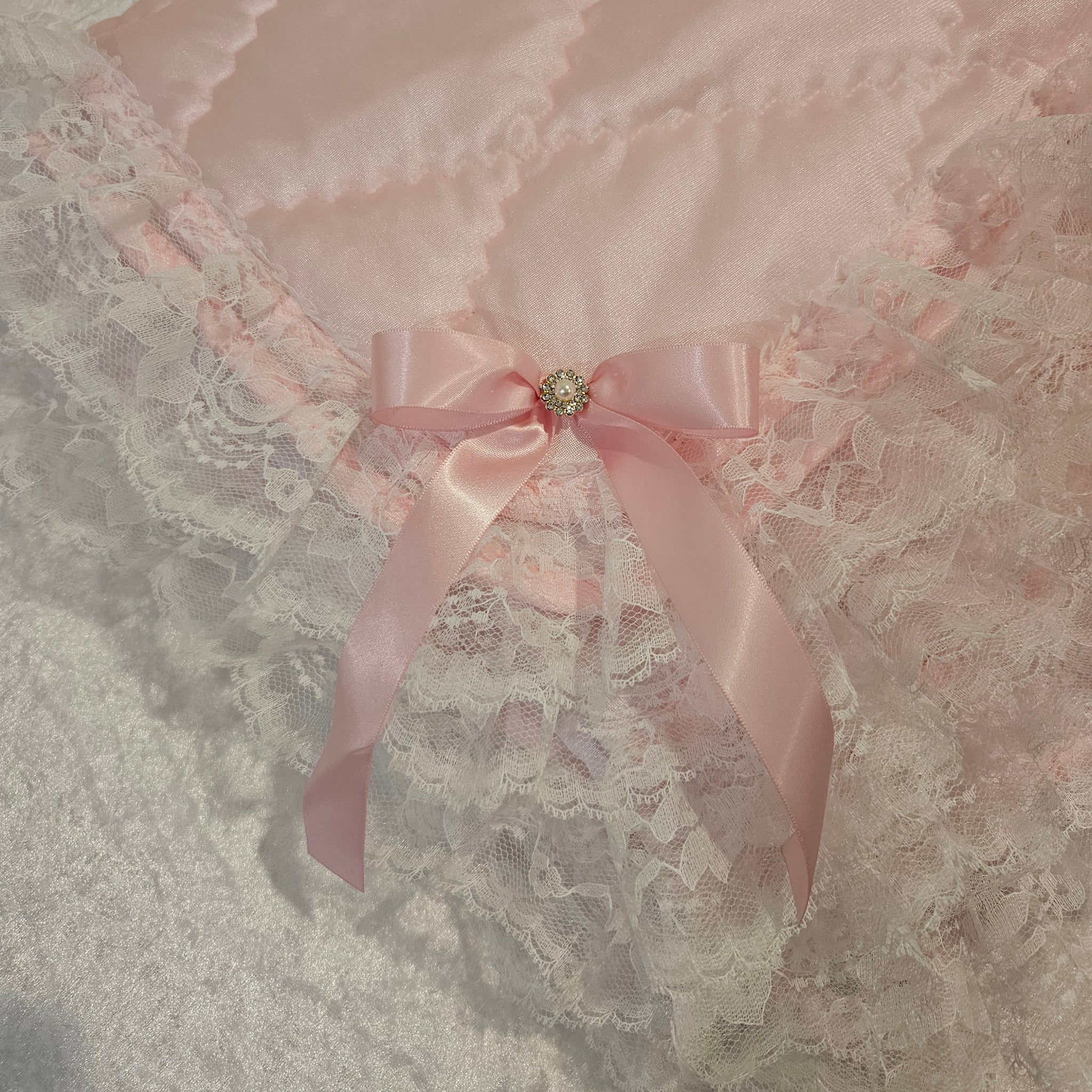 Close-up of a pink bow and lace with a decorative blanket on a textured fabric background