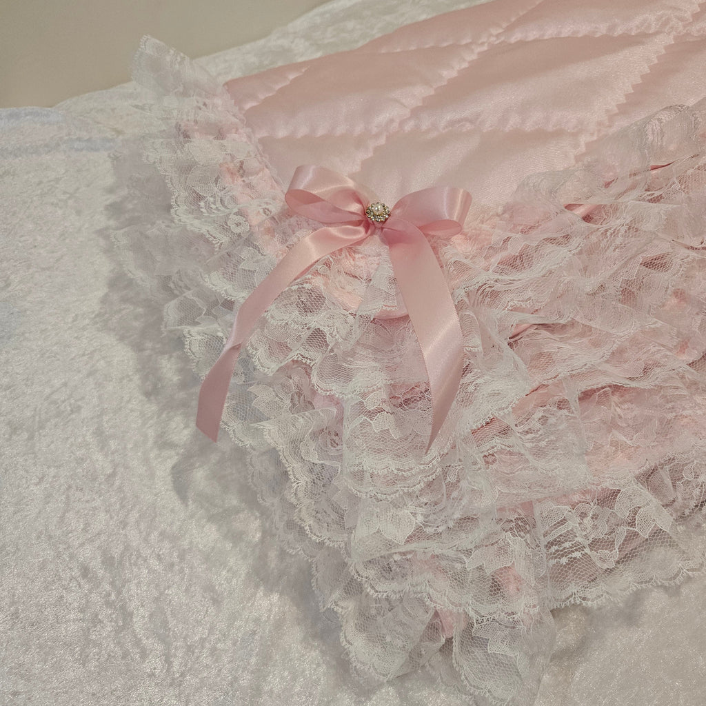 Pink lace snuggle blanket with a bow on a textured surface