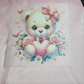 Cartoon teddy bear applique with a pink bow and heart surrounded by flowers on a light pink taffeta background