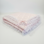 Folded pink lace blanket with a Pink satin bow with gem on a white background