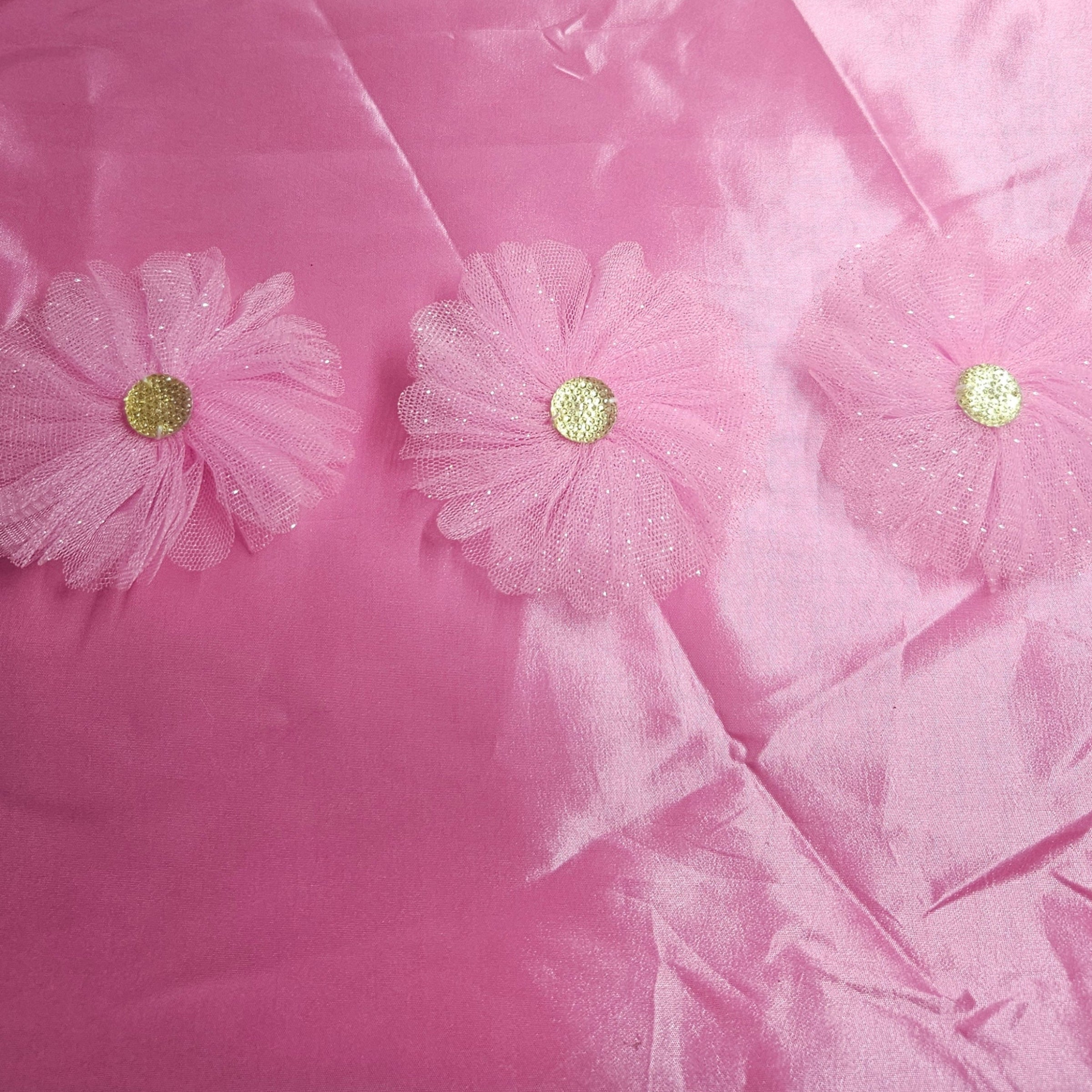 Close-up of pink taffeta fabric with floral embellishments on a pink background