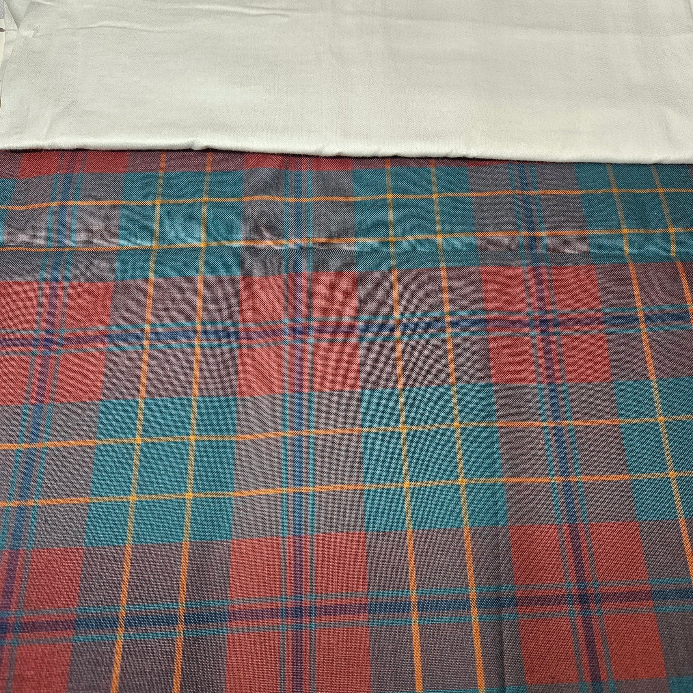 Plaid fabric with red, blue, and yellow pattern on a white background