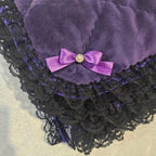 Purple snuggle blanket with a black lace trim and a purple bow on a textured beige background