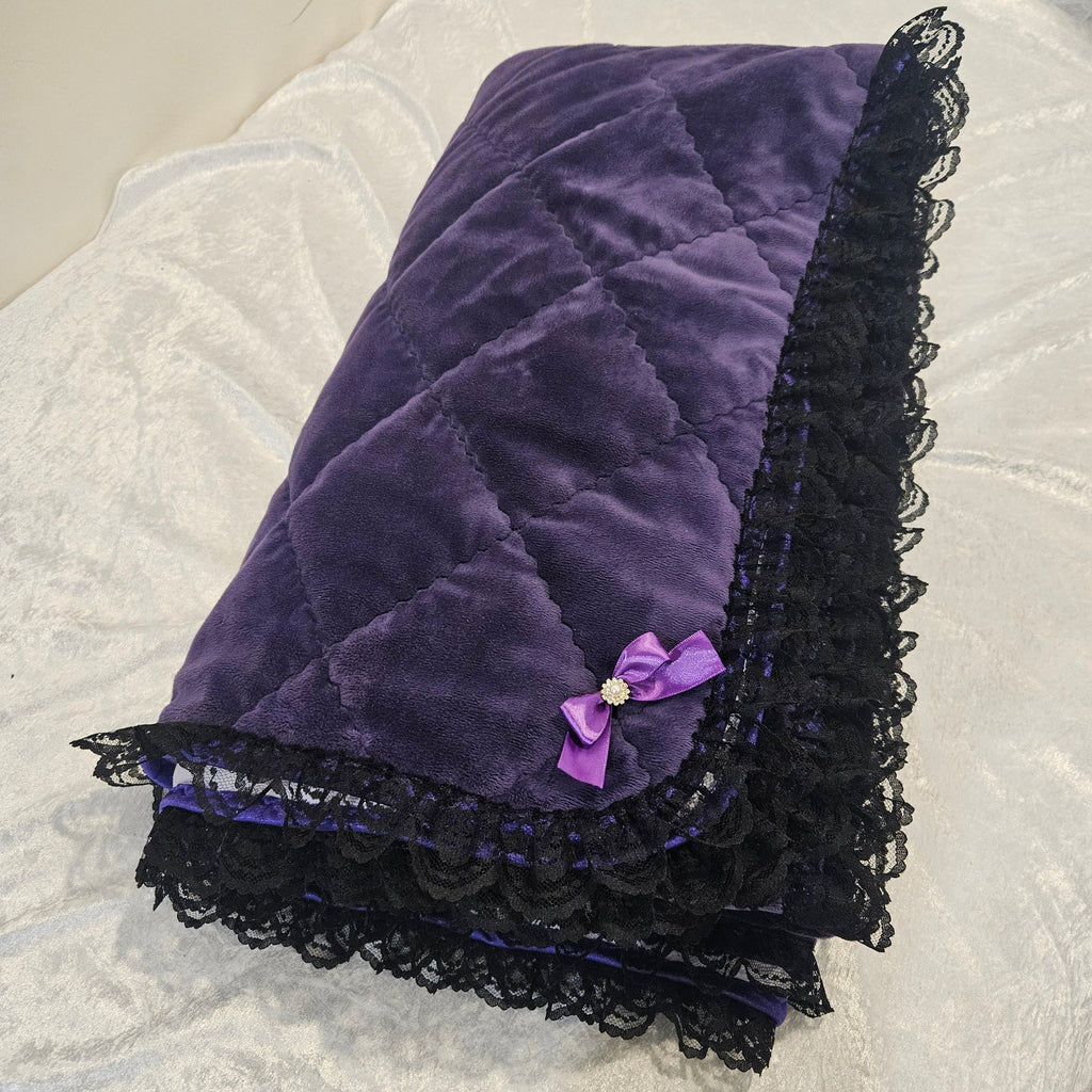 Purple snuggle quilted with black lace trim on a white textured surface