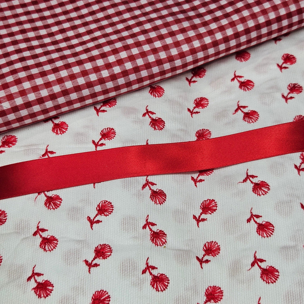 Red and white checkered fabric with red floral pattern on white background
