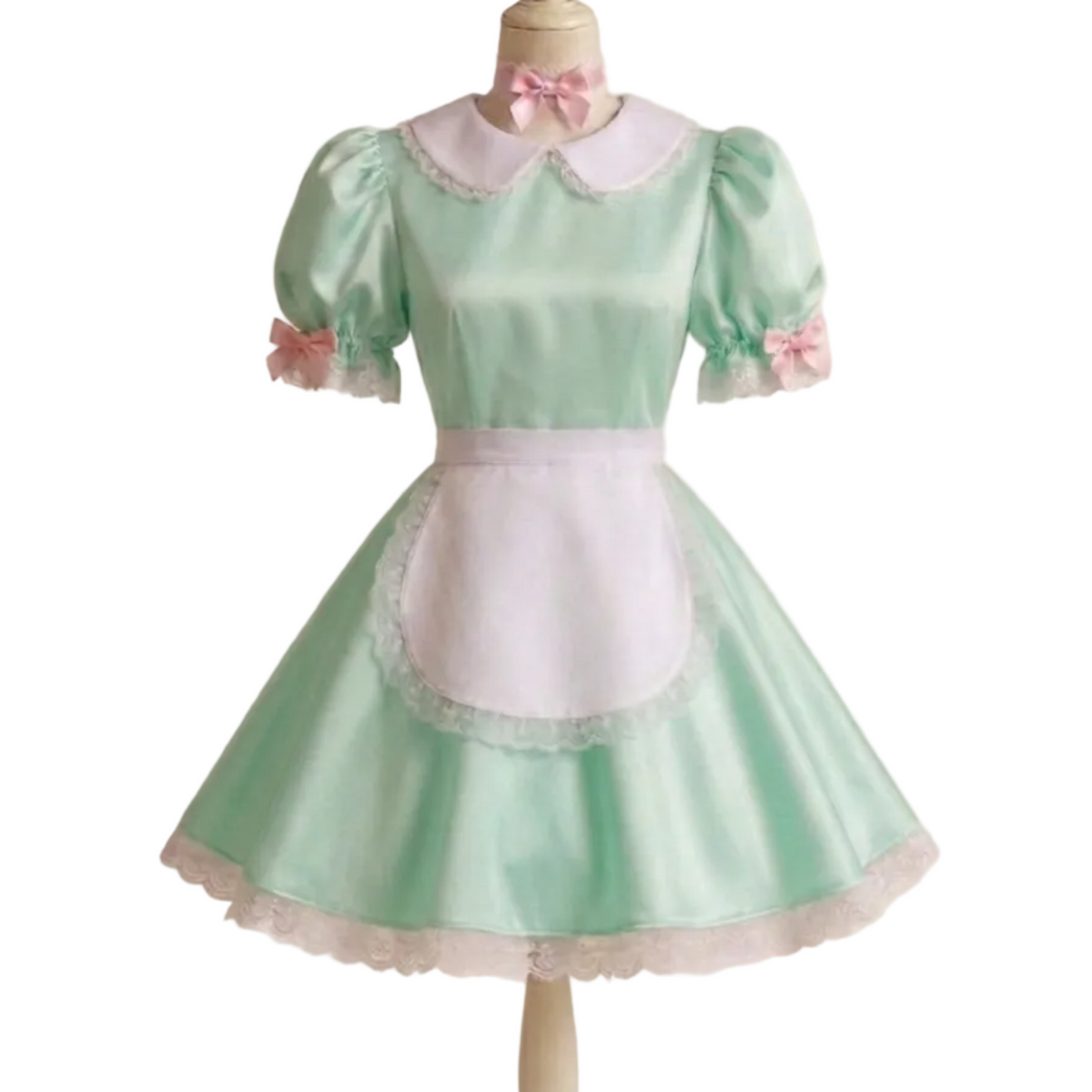 A light mint green and white maid outfit displayed on a wooden dress form mannequin. The dress features short puff sleeves, a white collar with lace trim, a pink bow at the neck, a white apron panel with lace trim, and pink bows  on the sleeves.