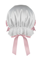 White bonnet with pink ribbons on a white background