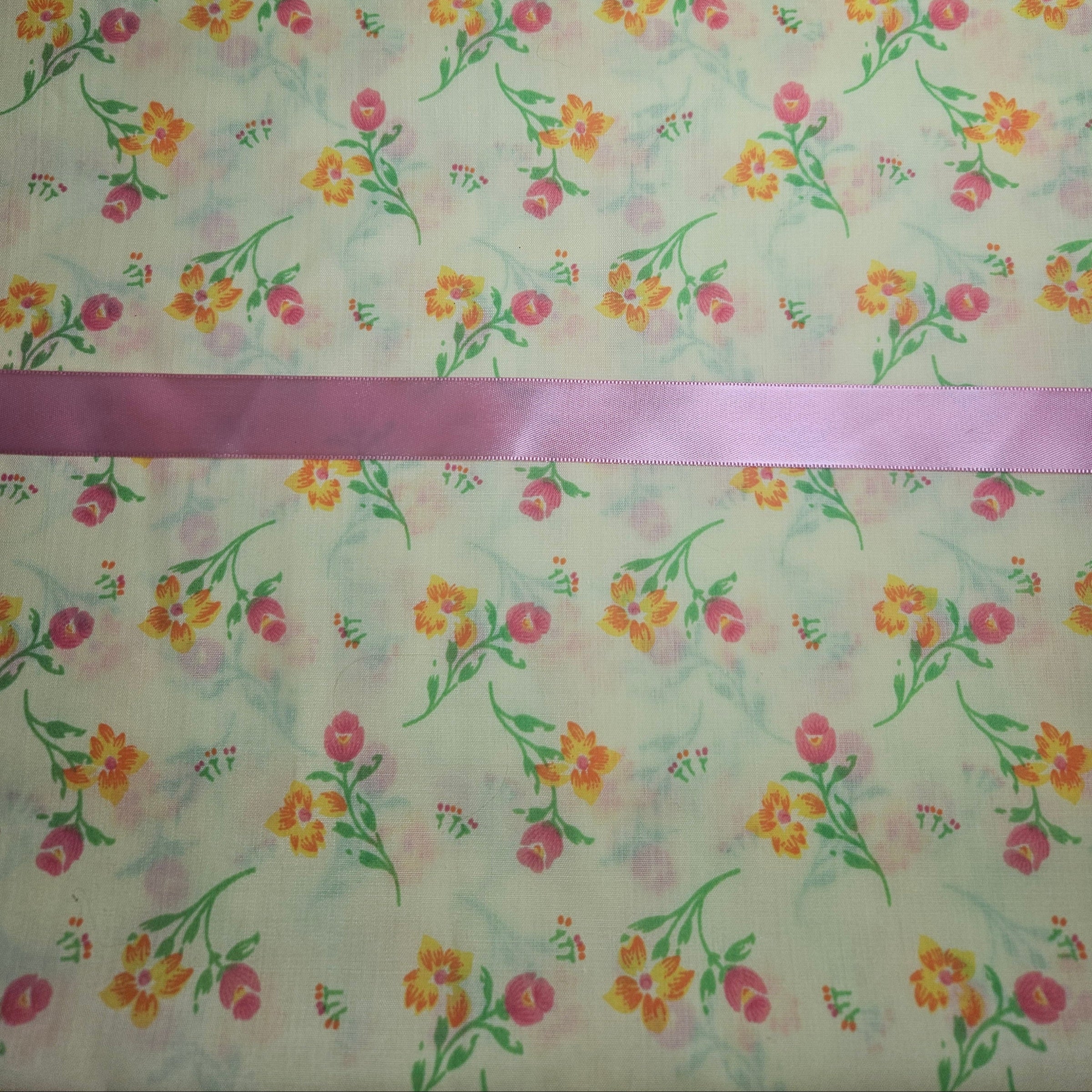 Floral patterned fabric with a pink ribbon on a yellow background
