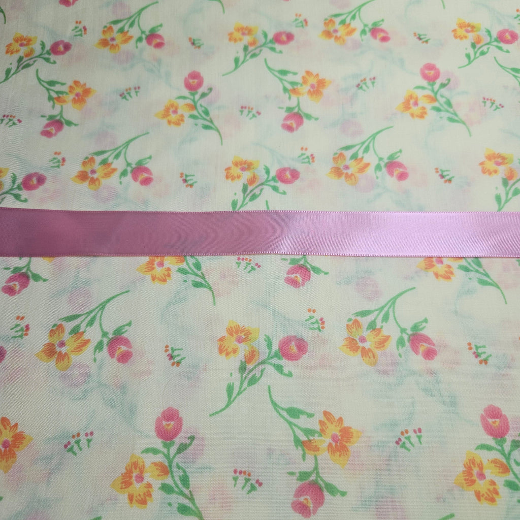 Floral patterned fabric with a pink ribbon at the top