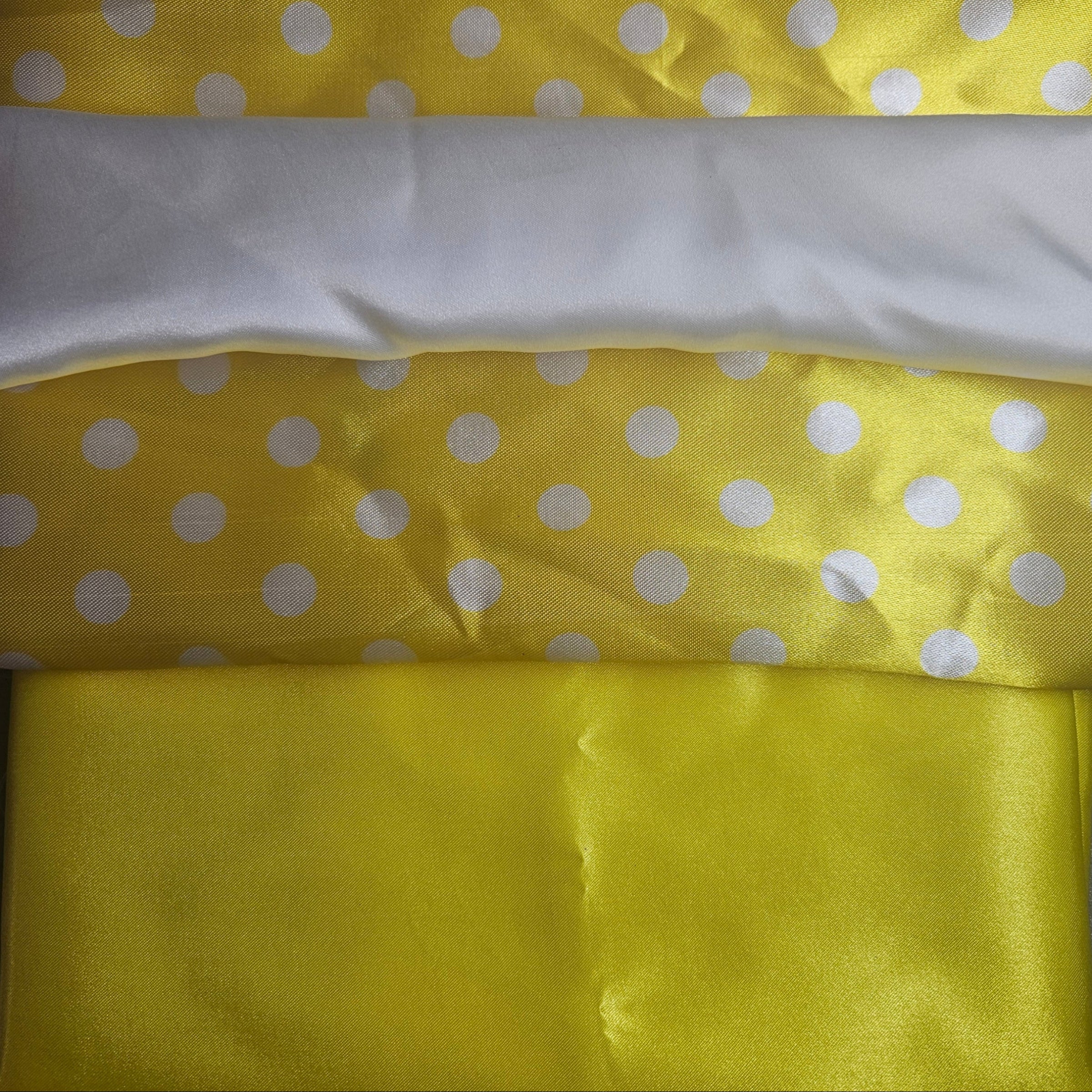 Yellow satin fabric with white polka dots and a white strip on top