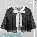Black lace cape with a white bow on a light gray background
