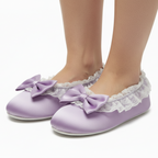 Purple slippers with bows and lace trim on a white background