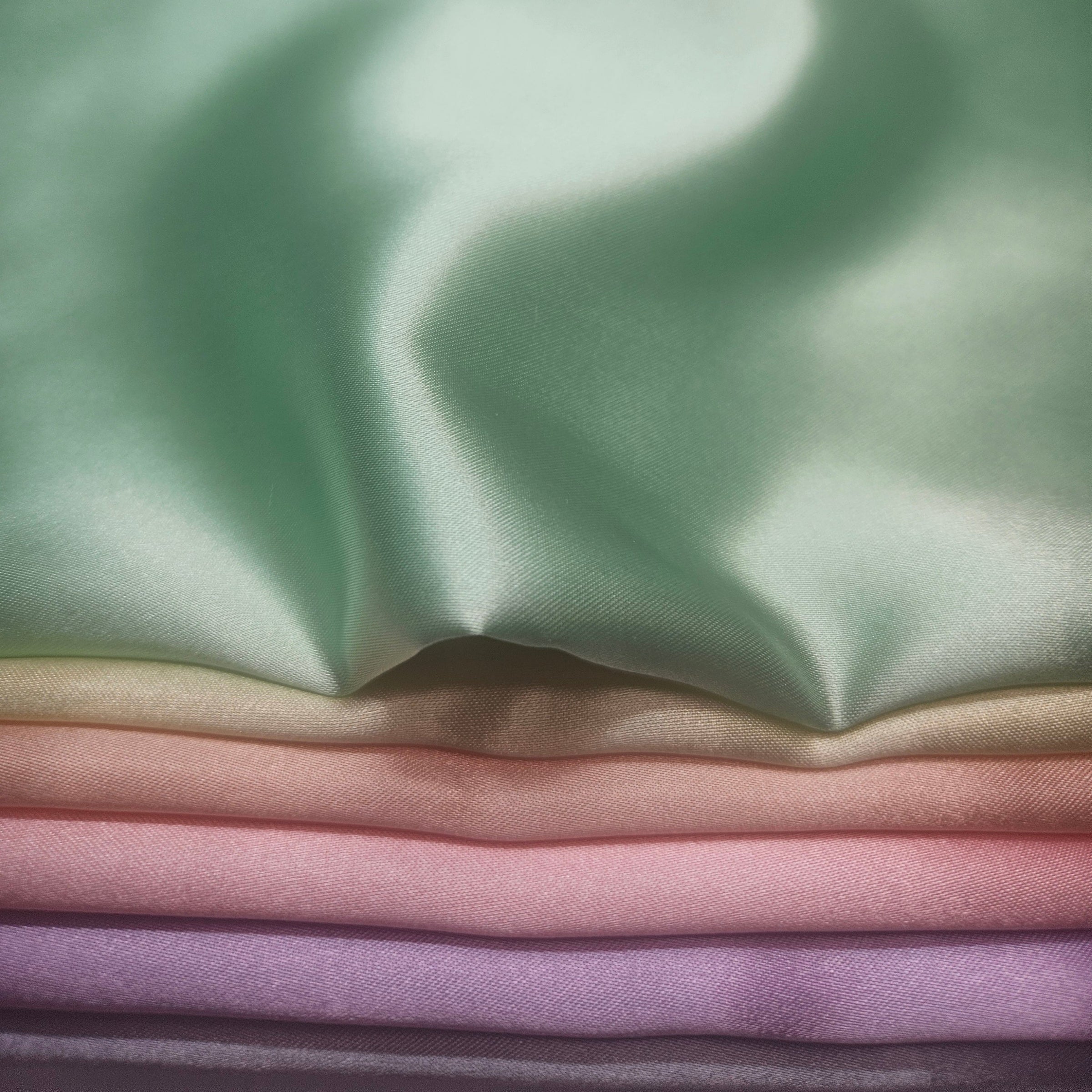 Stack of pastel-colored fabrics including yellow, peach, pink, purple, blue, & mint green
