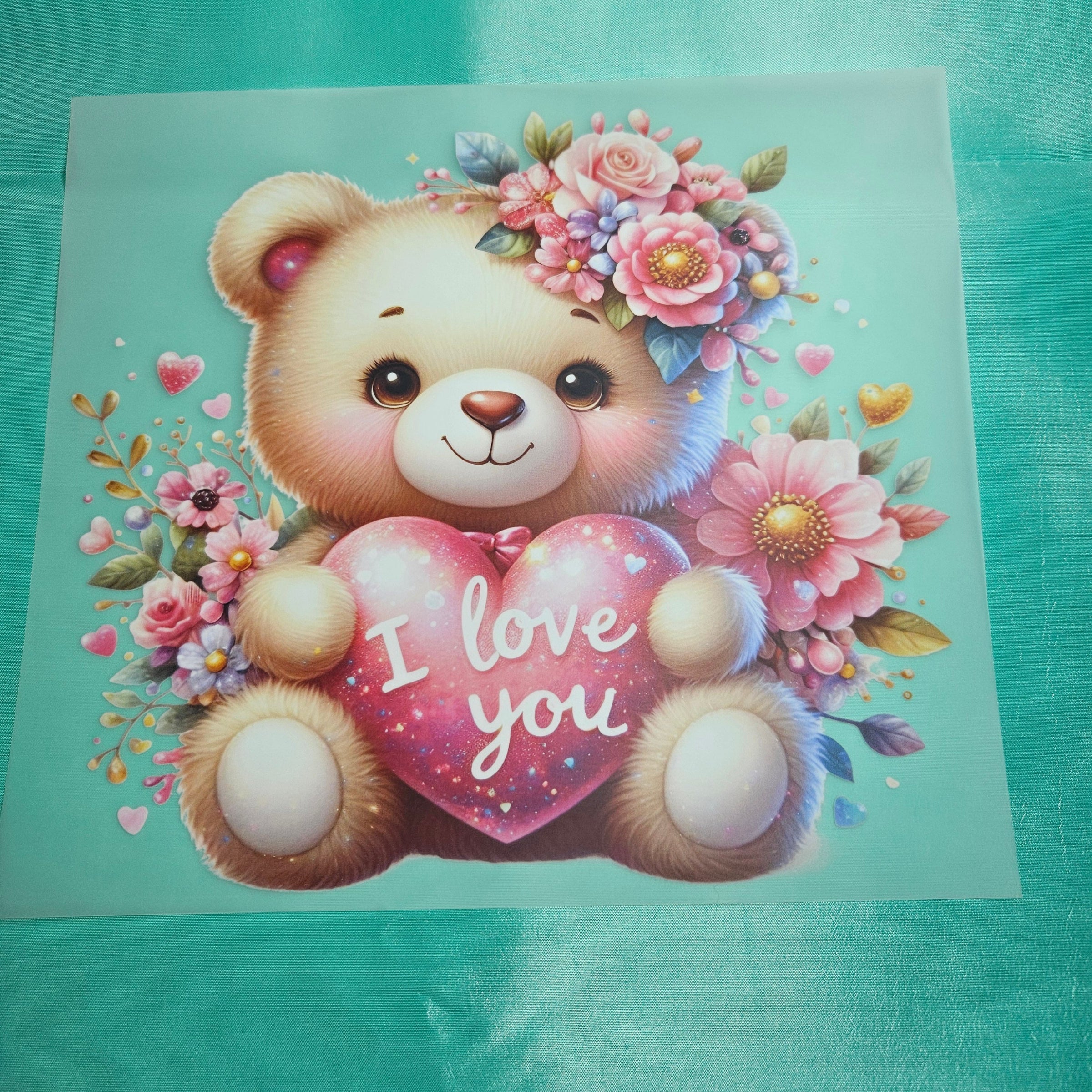 Cartoon teddy bear applique with flowers and 'I love you' heart on a light green taffeta background