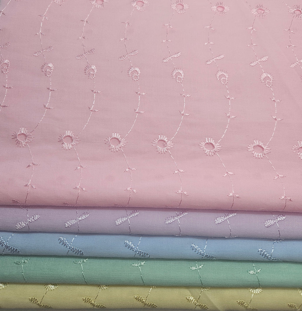 Stack of fabric swatches with floral patterns on a pink background