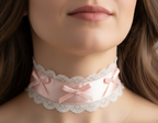 Close-up of a lace choker with pink ribbons worn by a person.
