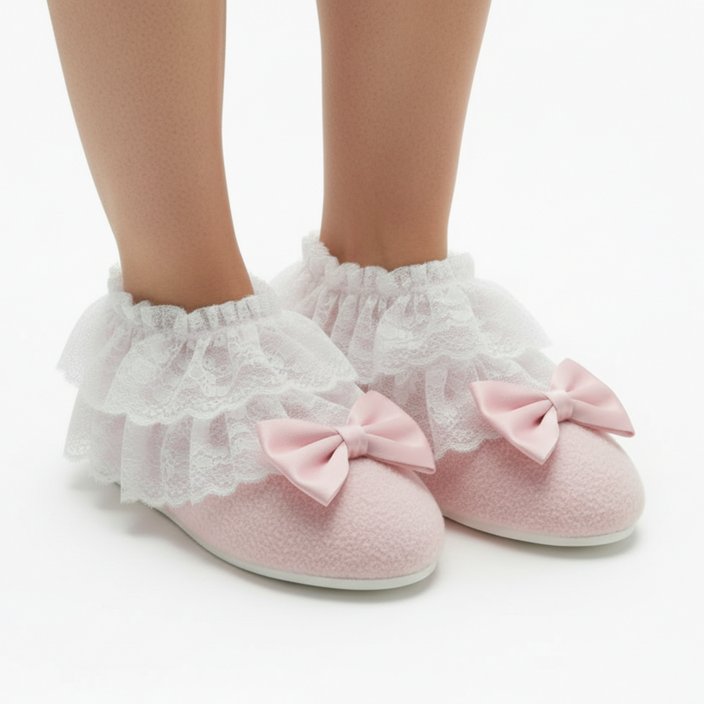 Pink slippers booties with ruffles and bows worn by a person on a white background