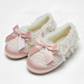 Pair of pink slippers with lace details and bows on a white background