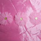 Pink taffeta fabric with floral embellishments on a pink background