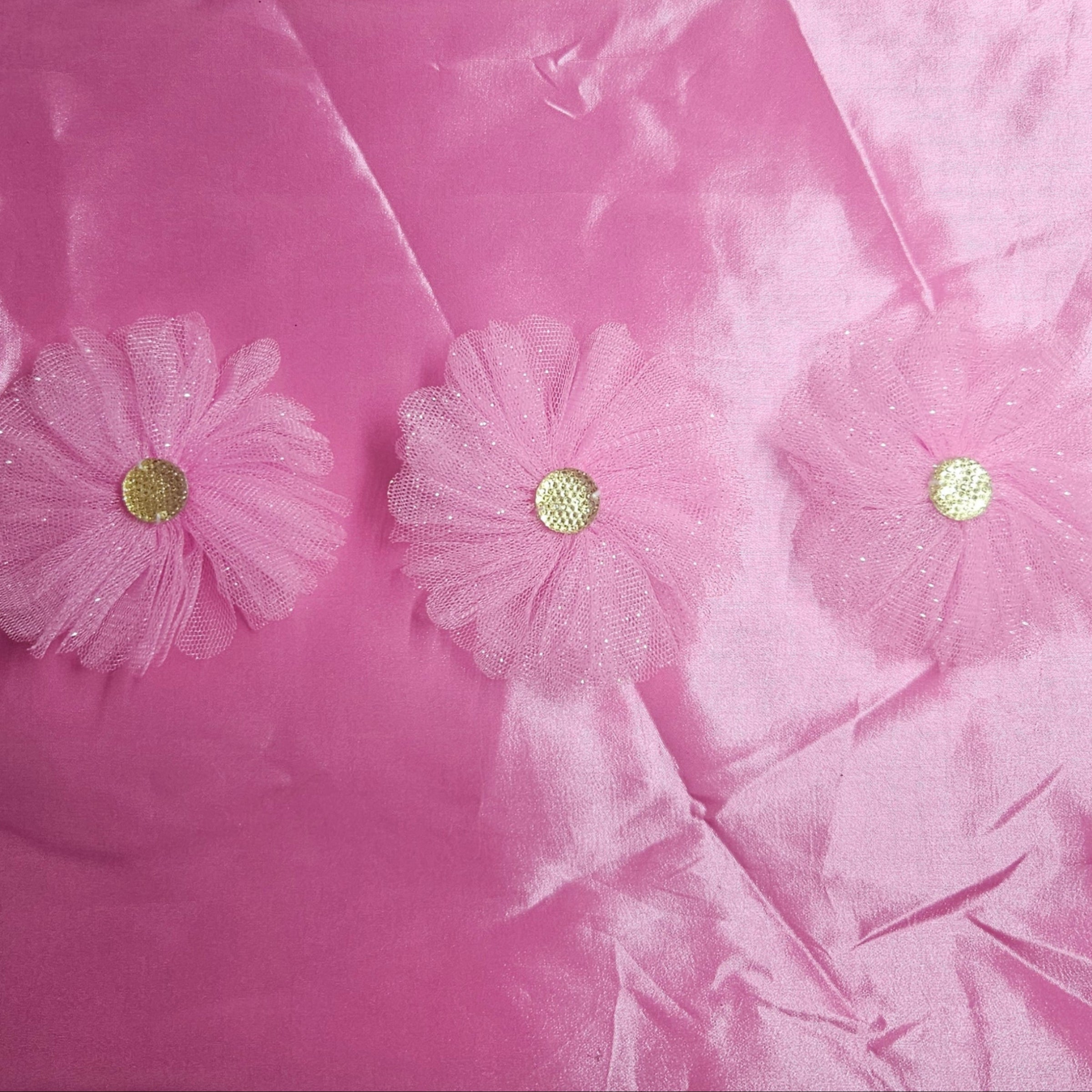 Pink taffeta fabric with floral embellishments on a pink background
