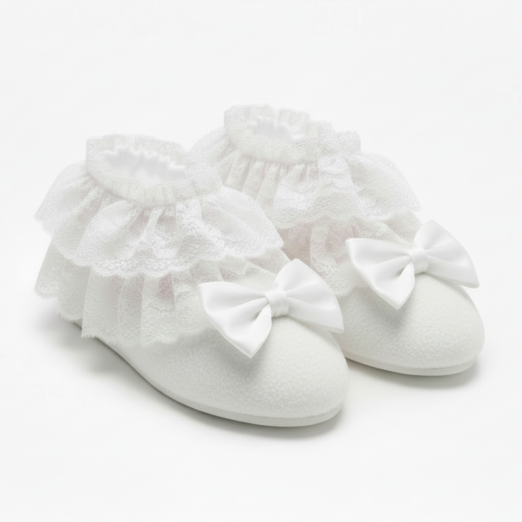White booties with ruffles and bows on a light gray background