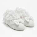 White booties with ruffles and bows on a light gray background