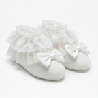 White booties with ruffles and bows on a light gray background